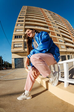 Person sits on a ledge near a building on a sunny day