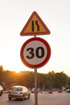 Speed limit and lane merge signs in sunset light