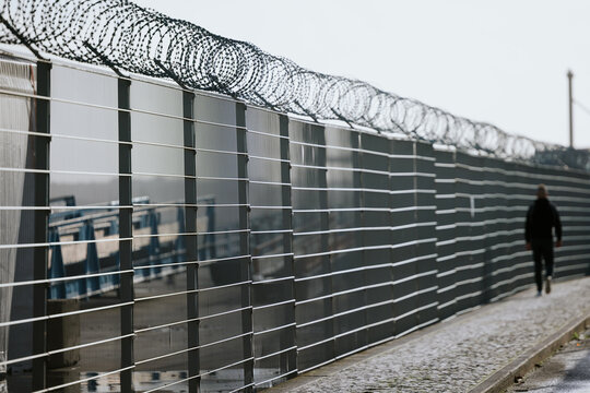 Barbed wire security fence along paved pathway