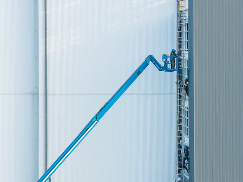 Workers Installing Panels on Industrial Factory Facade