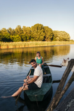 Two People Rowing a Boat on Calm Lake