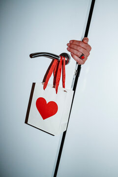 a man hand holding a door with a heart paper bag