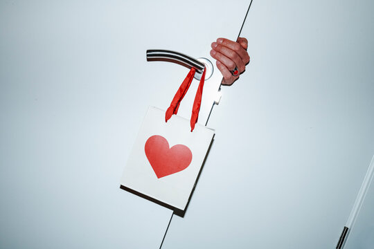 a paper bag with a red heart hangs from a door handle