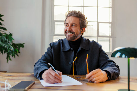 Man writing notes looking inspired at office