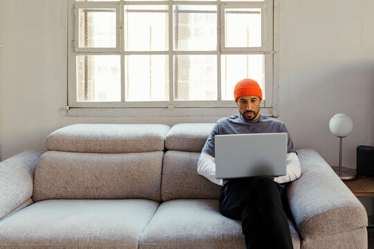 Man working on laptop sitting on sofa at office