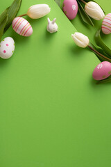 Fototapeta premium Colorful vertical decorated Easter eggs, white tulips and a small ceramic bunny arranged on a bright green background for spring celebration and seasonal greeting card layouts