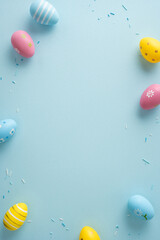 Obraz premium Bright vertical pastel decorated Easter eggs arranged around a blue background with sprinkles and empty space for text conveying Happy Easter celebration and springtime joy