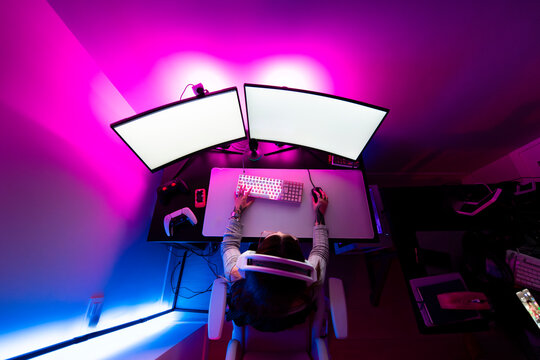 Anonymous female gamer playing at vibrant pc desk