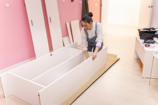 Woman tightening screws on partially assembled wardrobe