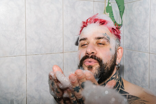 A man blows on the foam in the bathtub