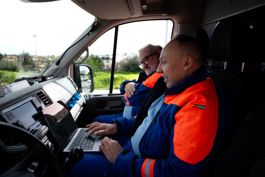 Paramedics using laptop inside emergency ambulance van
