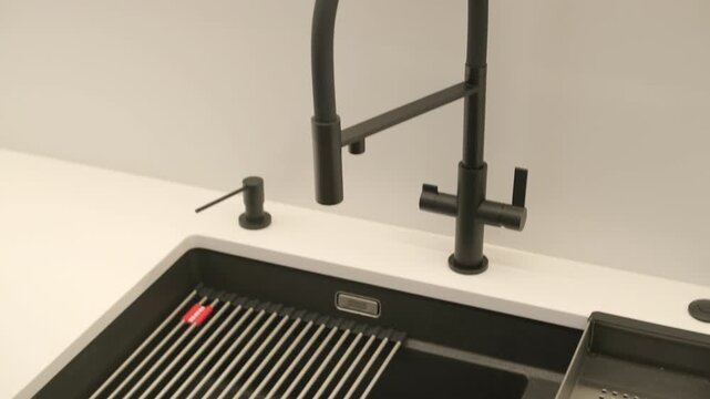 Modern black granite kitchen sink with matte black faucet and drying rack.
