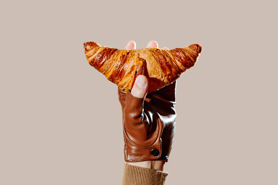 a croissant balanced on a gloved hand