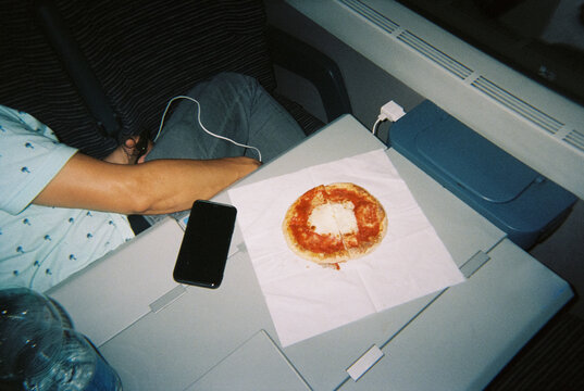 a casual train meal beside a charging phone, 35mm film
