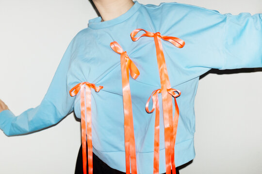 Person wearing a fashion style blue shirt with pink silk ribbon bow 