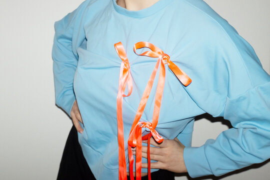 Person wearing a fashion style blue shirt with pink silk ribbon bow 