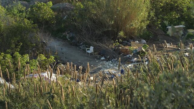 Dirt and trash in a field next to some shacks