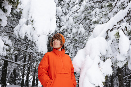 Winter Explorer in Bright Orange Coat Standing Amid Snowy Forest Trees