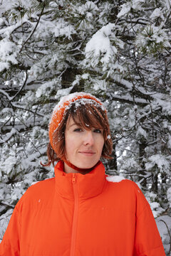 Woman in Orange Winter Jacket and Headscarf Enjoying Snowy Forest