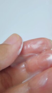 White cream liquid anti dandruff shampoo on fingertips, white background, close up view, hair care product, cleansing treatment, cosmetic concept.