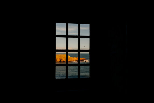 Ocean cliffs seen through dark window frame