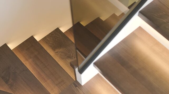 Modern wooden staircase with integrated LED strip lighting, glass balustrade