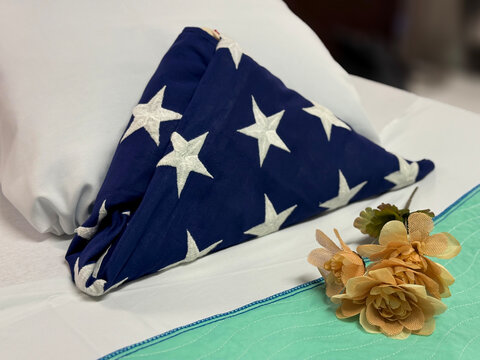 Folded American Flag on Hospital Bed with Memorial Flower, Veteran Remembrance and Military Honor Concept
