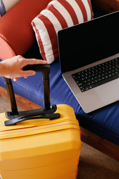 Business travel essentials: Hand holding suitcase handle near laptop