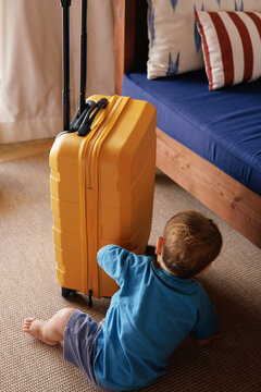 Child reaching for yellow suitcase in living room