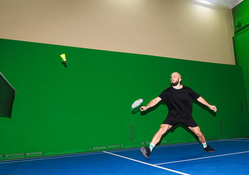 Player Hits Shuttlecock in Indoor Badminton Court