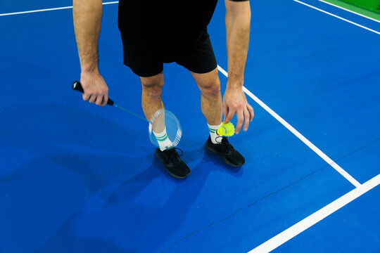 Player Prepares for a Badminton Game on a Blue Court