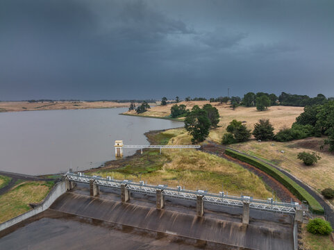Heavy rain advancing over a rural reservoir and spillway