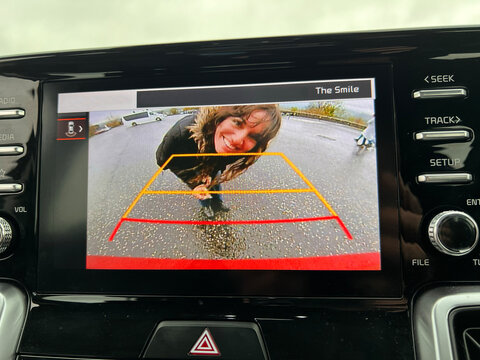 Smiling woman looking into the reverse camera of a car 