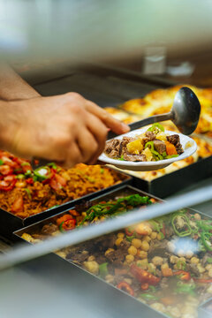 Hand serving stew from buffet counter