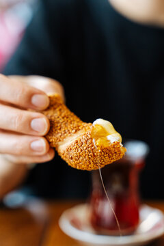 Hand holding simit with melted cheese