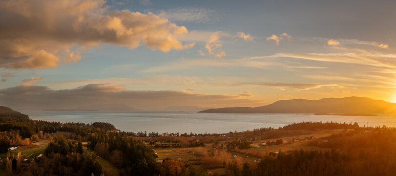 Sunset over Orcas Island with beautiful warm light located in the San Juan Islands and the Salish Sea. Aerial panoramic drone shot seen from Lummi Island, Washington, USA. 