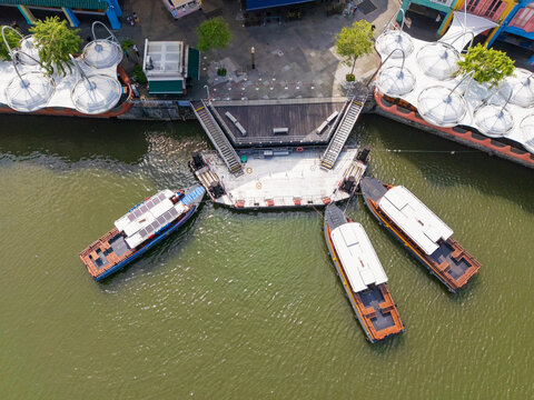 Tourist boast docked at a waterfront deck between white sunshades