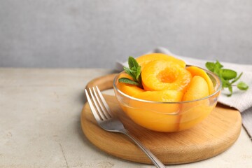 Pickled peaches and mint leaves in bowl on light grey table, closeup. Space for text © New Africa