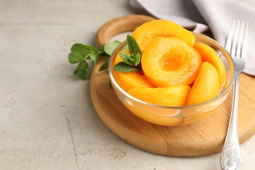 Pickled peaches and mint leaves in bowl on light grey table, closeup. Space for text © New Africa