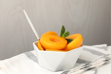 Pickled peaches and mint leaves in bowl on white table, closeup © New Africa