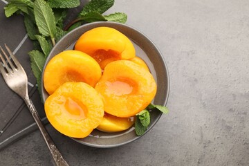 Pickled peaches and mint leaves on grey table, flat lay. Space for text © New Africa