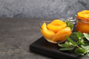 Pickled peaches and mint leaves on grey table, closeup. Space for text © New Africa