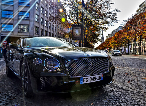 Paris, France &ndash; October 26th 2019: A brown Bentley Continental turning on Avenue George V, lined with colorful autumn trees in a sunny upscale district.