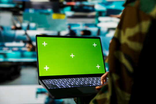Green screen mockup laptop used by army officer using reconnaissance tech to do threat monitoring and target recognition. Woman employing warfare intelligence using chroma key notebook software