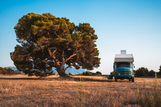 expedition truck parked under large tree in rural greece
