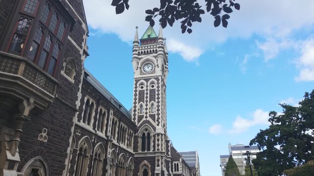 Iconic university of otago registry building, also known as the clocktower building, on a sunny day with clouds passing in dunedin, new zealand