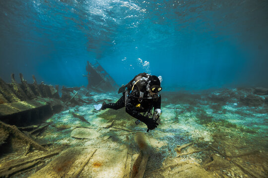 Young scuba diver swimming across sunken ship deck