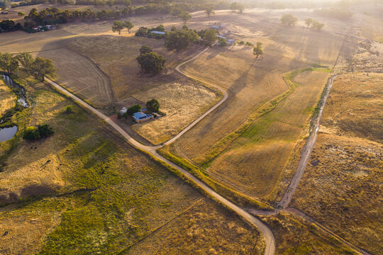Country road zig zagging up a hillside past a rural farmhouse