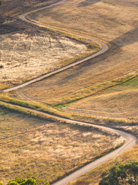 Dirt road zig zagging up a dry hillside in golden light
