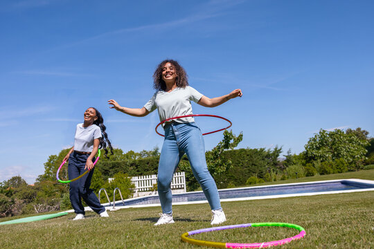 Friends enjoying hula hooping in sunny park